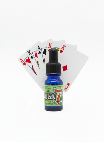 lucky 7 pheromone cologne bottle with a pair of aces behind the bottle and a triple of kings. playing cards. 